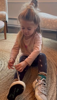 Picture of a little girl learning how to tie her shoe